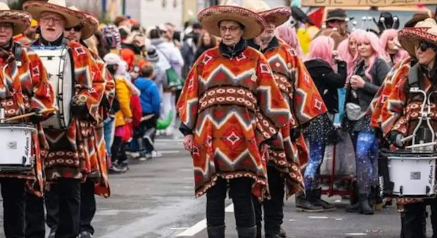 Menschen in bunten Ponchos und Sombreros marschieren mit Trommeln. Sie feiern Fasching, eine Zeit voller Freude und Verkleidungen.