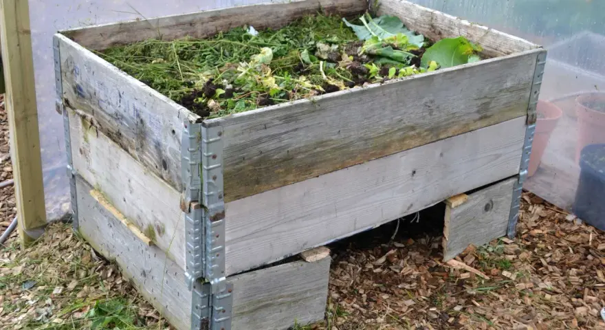 En kompost av pallkragar fylld med trädgårdsavfall. Enkel och effektiv lösning för att bygga kompost.