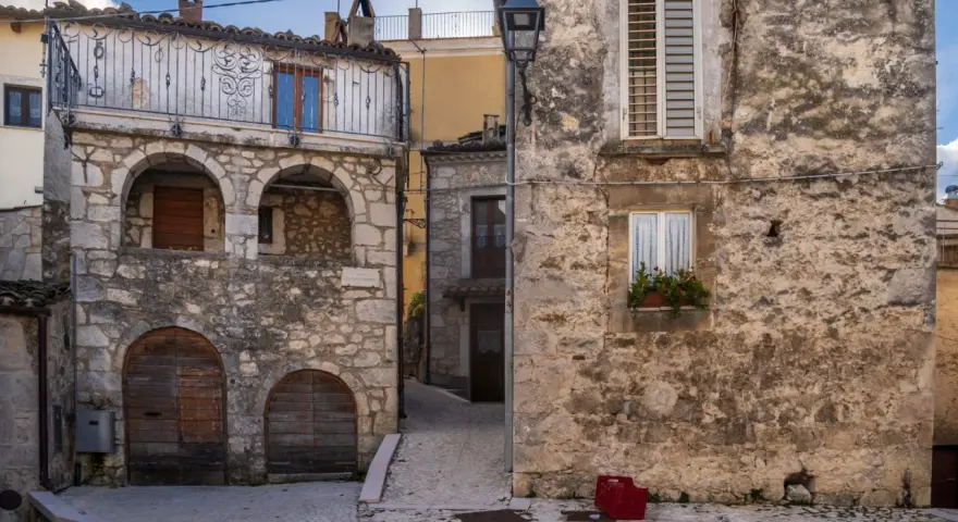 Antico borgo in pietra, con archi e balcone in ferro battuto. La **pretoro altitudine** offre scorci suggestivi tra vicoli acciottolati e case antiche.