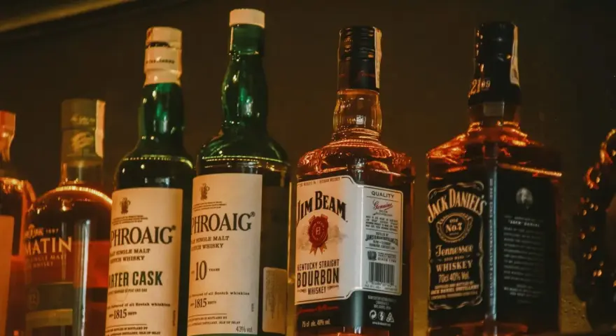 Rząd butelek whisky, w tym Laphroaig, Jim Beam i Jack Daniel's, idealny jako dobre whisky na prezent.