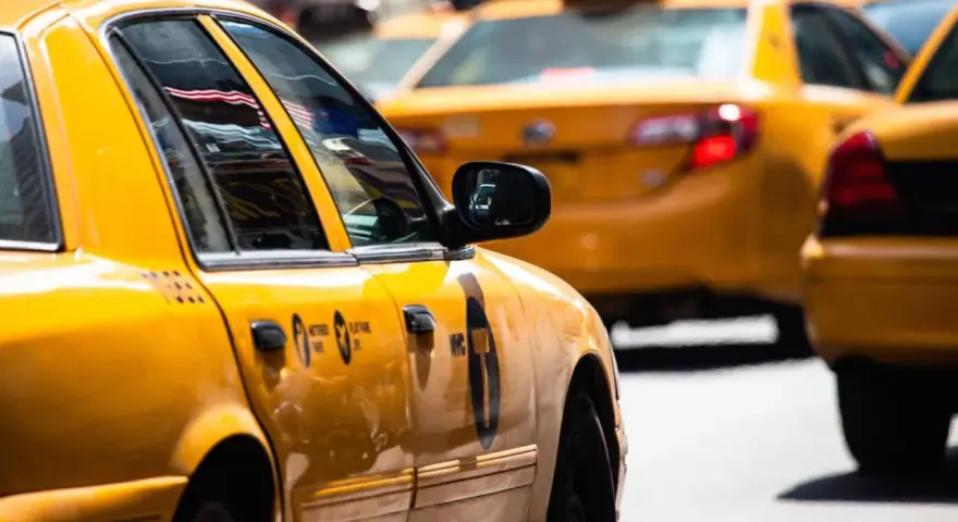 Gelbe Taxis in den USA, ein ikonischer Anblick. Die Spiegelung der US-Flagge im Fenster des vorderen Taxis.