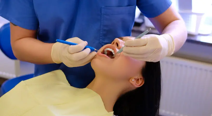 Dentysta wykonuje fluoryzację zębów pacjentki, dbając o ich zdrowie i ochronę przed próchnicą.