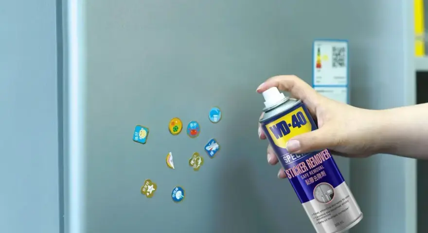 Jak usunąć naklejkę z szyby? Puszka WD-40 Sticker Remover w dłoni, gotowa do działania na lodówce.