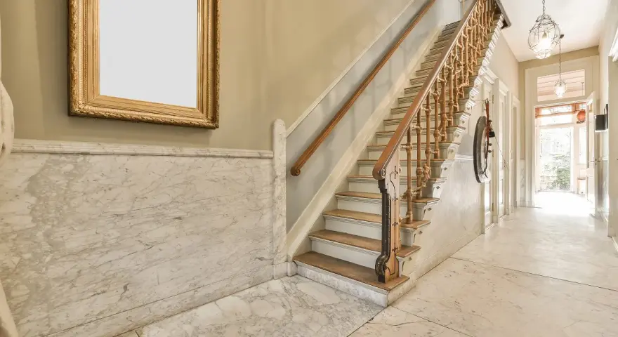 Elegante rellano de escalera comunitaria con mármol y un cuadro dorado. Ideas para decorar rellano escalera comunidad.