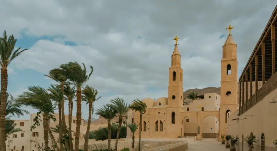 A monastery courtyard with palm trees and a bell tower, evoking the spirit of the desert fathers and mothers.