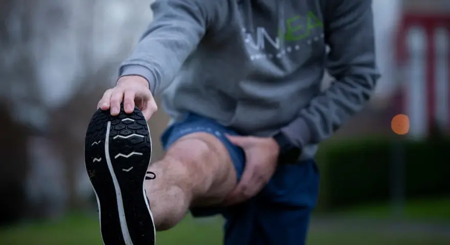 Hombre estirando la pierna antes de correr con agujetas.