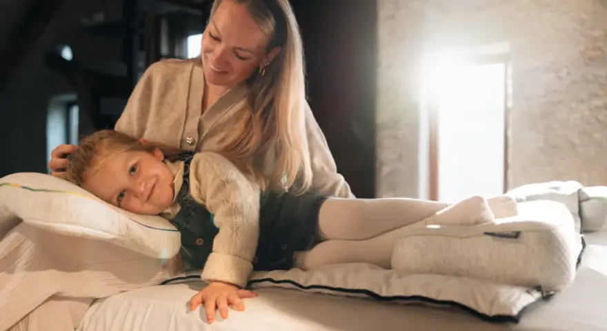 Mutter streichelt Kind, das auf einem Kissen liegt. Gute Nacht-Tipps für Kinder 11 Jahre.