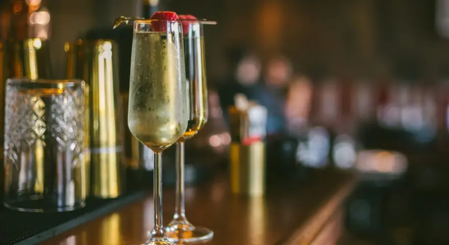 Dwa kieliszki musującego drinka z maliną na wierzchu. Idealne na domowe przyjęcie, inspiracja do drinki przepisy domowe.