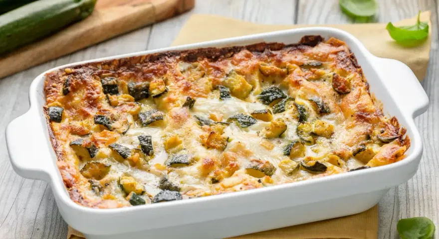 Lasagne di zucchine appena sfornate, dorate e filanti, con zucchine a cubetti e formaggio fuso.