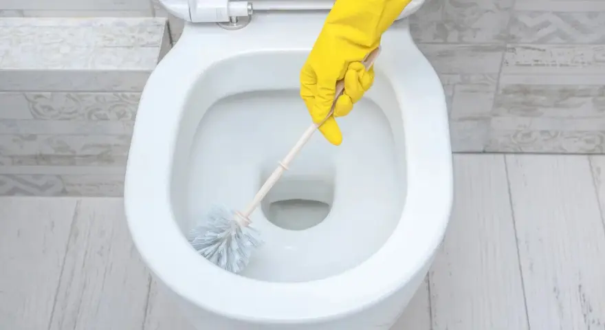 Main jaune pour nettoyer les toilettes.