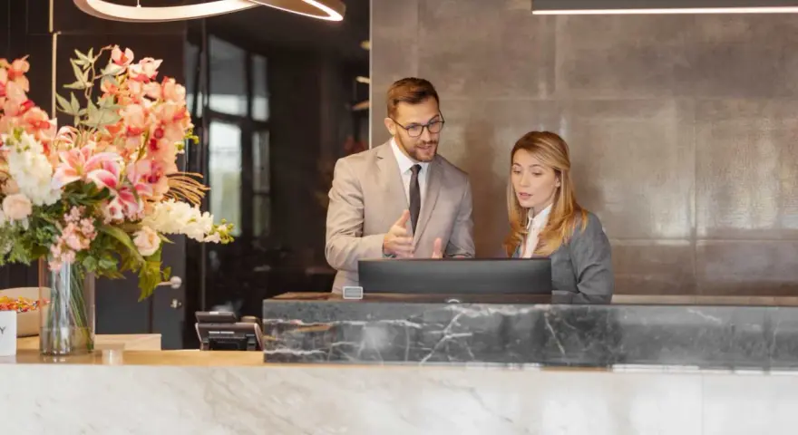 Professionnels discutent d'un calcul d'indemnité d'éviction pour un bail commercial de résidence de tourisme, devant un ordinateur.