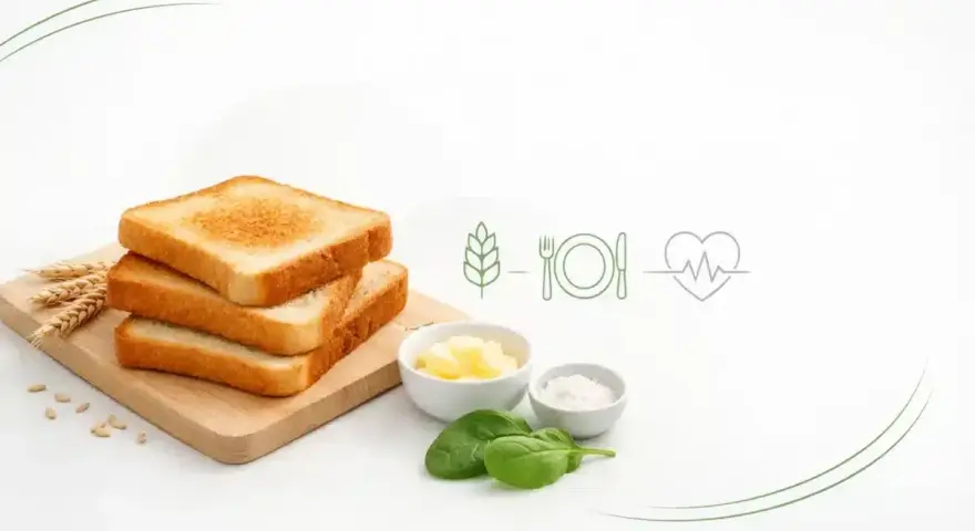 Stosik rumianego chleba tostowego pełnoziarnistego na desce, obok masło, sól, szpinak i symbole zdrowego żywienia.