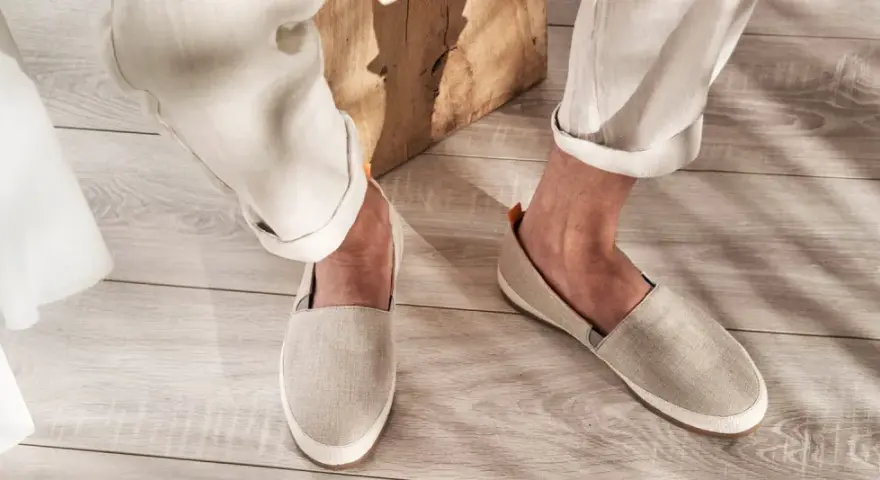 Un uomo indossa espadrillas in tela beige con pantaloni chiari arrotolati. Perfette per un look casual estivo, scopri come abbinarle.