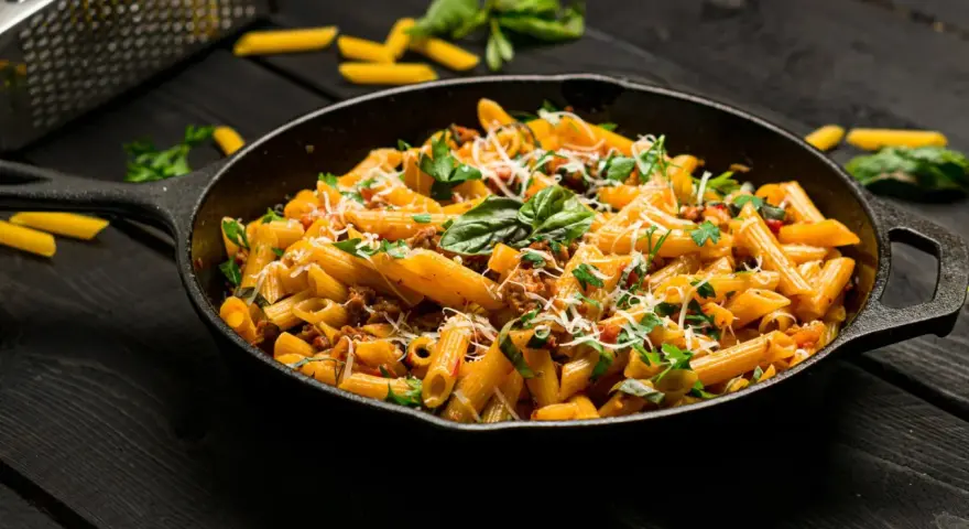 Makaron penne z mięsem mielonym i ziołami w żeliwnej patelni.