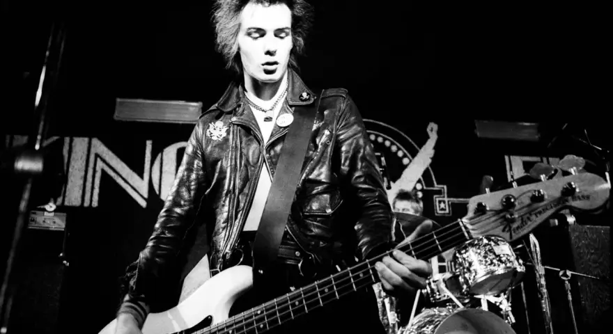 Sid Vicious, Punk-Ikone, spielt Bass auf der Bühne. Seine wilden Haare und Lederjacke unterstreichen seine rebellische Ausstrahlung. Seine Musik erfüllt die "sid wishes" des Publikums.