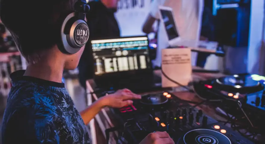 Młody DJ ćwiczy na sprzęcie, słuchawki na uszach. To świetny moment na rozpoczęcie kursu DJ online i naukę miksowania.