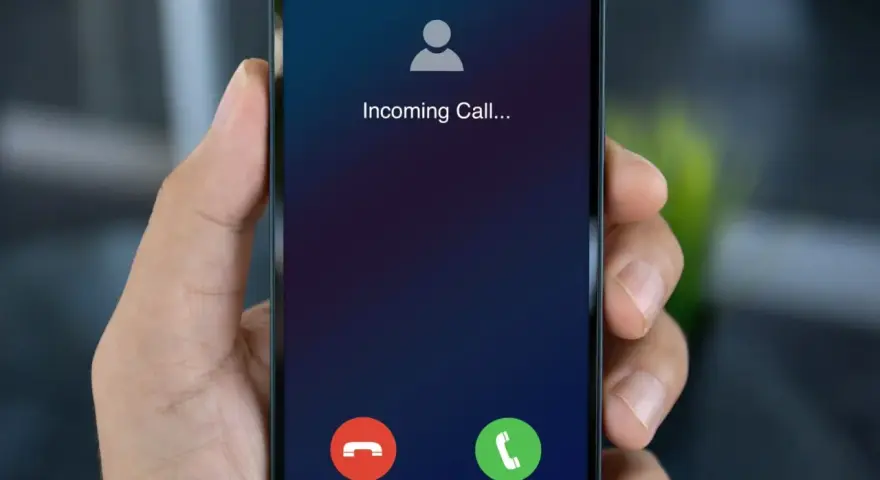 Dłoń trzyma smartfon z ekranem "Incoming Call...". Czy to połączenie z zagranicy, gdy działa co to roaming?