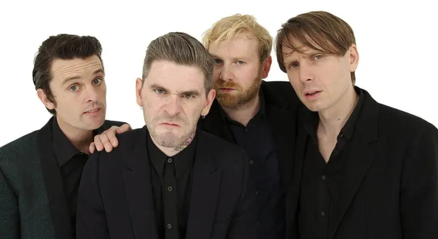 Les membres de Franz Ferdinand posent ensemble, quatre hommes aux regards intenses et aux coiffures stylées, prêts à enflammer la scène.