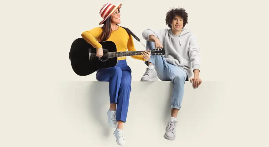 Frau mit Gitarre und Mann sitzen nebeneinander. Sie üben für ihren **spanisch austausch** und singen gemeinsam.