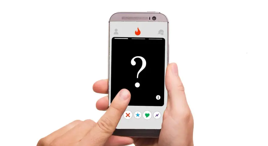 Dłoń trzyma smartfon z aplikacją randkową. Na ekranie widnieje znak zapytania i ikony: X, gwiazdka, serce, błyskawica. To **Tinder oznaczenia** – decyzja należy do Ciebie!
