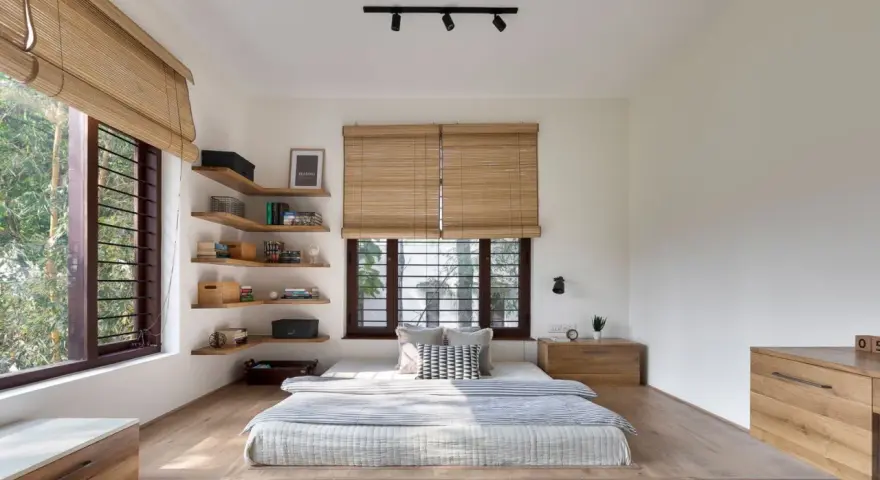 Habitación con cama baja, estanterías de madera y persianas de bambú. Un ejemplo de estilos de habitaciones minimalistas y acogedoras.