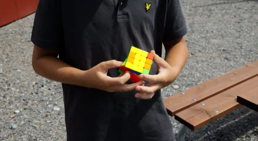 Ungdom med en färgglad Rubiks kub i händerna, redo för rubiks kub speed.