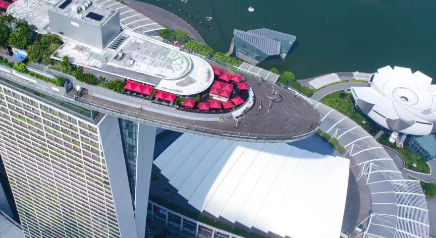 Widok z lotu ptaka na słynny singapur hotel statek z czerwonymi parasolami i basenem na dachu.