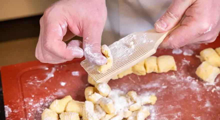 Hände formen Gnocchi mit einem Gnocchi-Brett. Köstliche italienische Gnocchi Rezepte beginnen so.