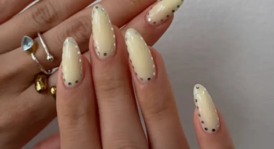 Modne paznokcie wzory galeria: kremowe migdałki z błyszczącymi kropkami. Delikatny manicure, który przyciąga wzrok.