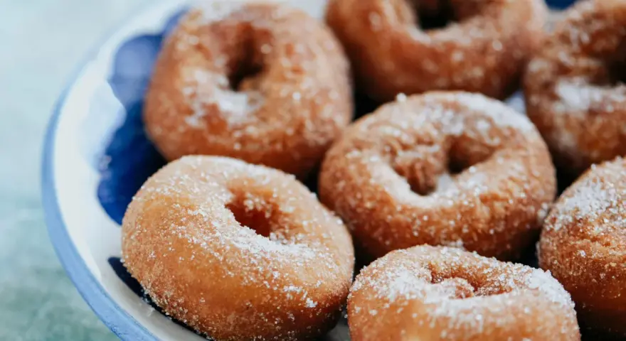 Rosquillas caseras de toda la vida, doradas y espolvoreadas con azúcar, listas para disfrutar.