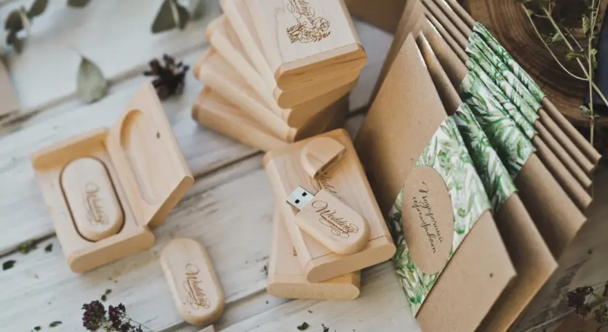 Drewniane pendrive'y z grawerem "Wedding" i koperty z motywem roślinnym. Personalizowane upominki dla gości od pary młodej to klucz do sukcesu.