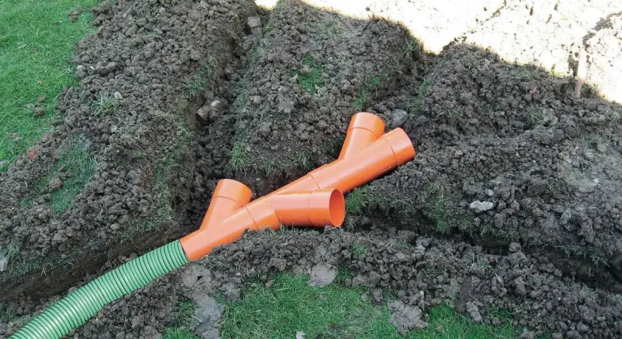 Tubi arancioni a Y e un tubo verde in una trincea: il sistema per capire come drenare il terreno.