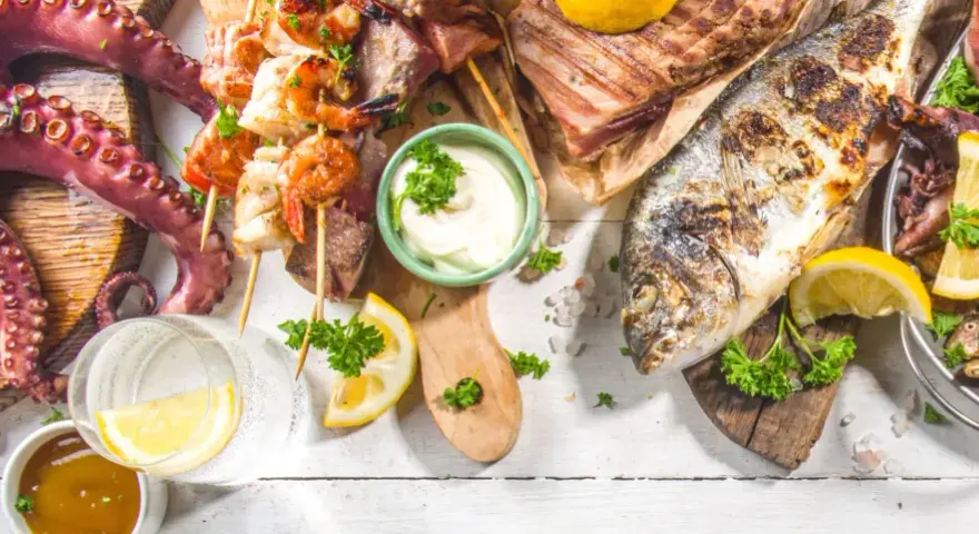 Un'abbondante grigliata di pesce con polpo, gamberi, calamari, aragosta e pesce intero, guarnita con limone e prezzemolo.