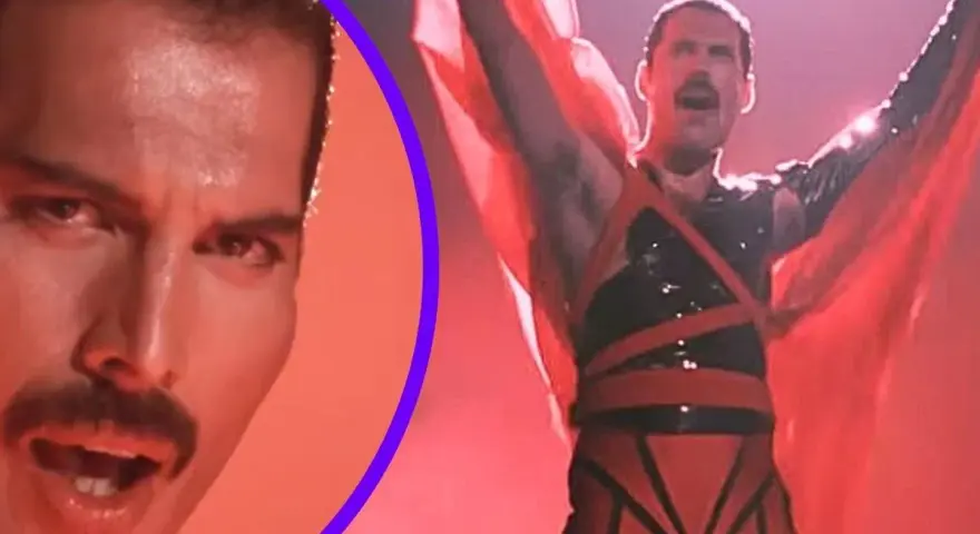 Freddie Mercury w czerwonym stroju, z rękami w górze, promuje swój **freddie mercury solo album**. Obok jego twarz z charakterystycznym wąsem.