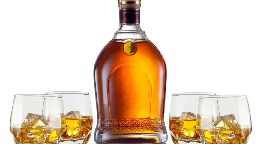 Elegancka butelka whisky i cztery szklanki z lodem. Czy to single malt czy blended, każdy znajdzie coś dla siebie.