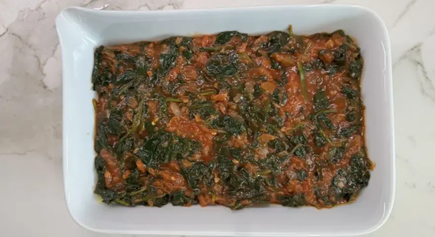 Lasaña de espinacas en salsa de tomate en un plato blanco.