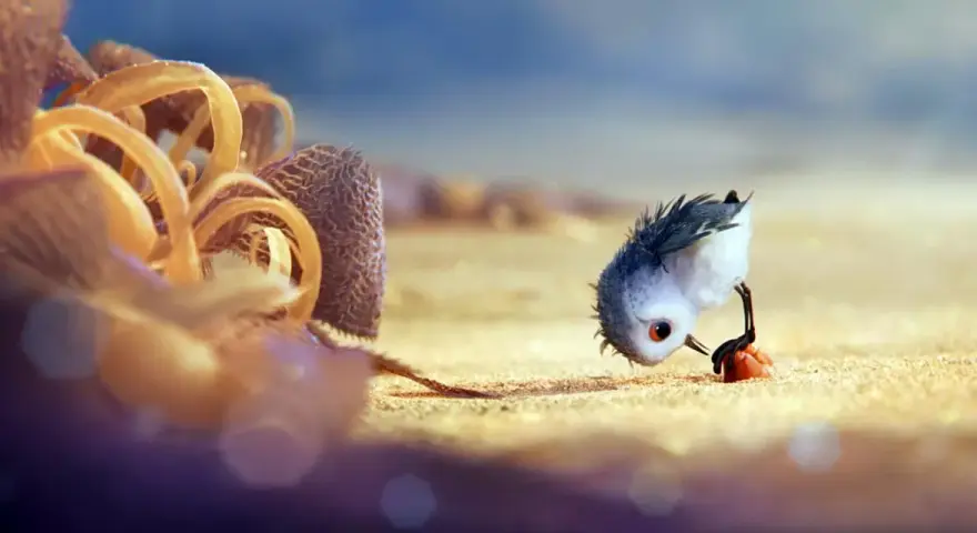 Un pulcino spaventato cerca cibo sulla spiaggia, un'immagine che cattura il significato del cortometraggio "Piper" sulla crescita e il coraggio.