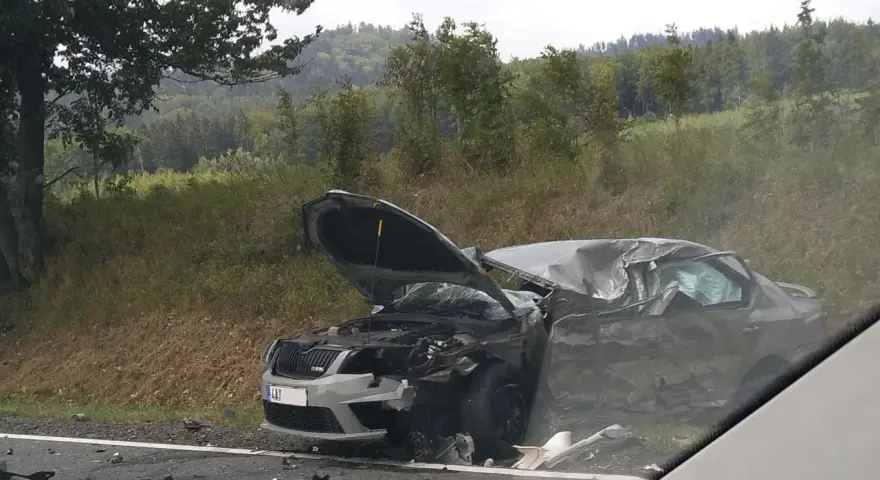 Zniszczony samochód po wypadku, maska otwarta, widoczne uszkodzenia. DKL rejestracja widoczna na przodzie pojazdu.