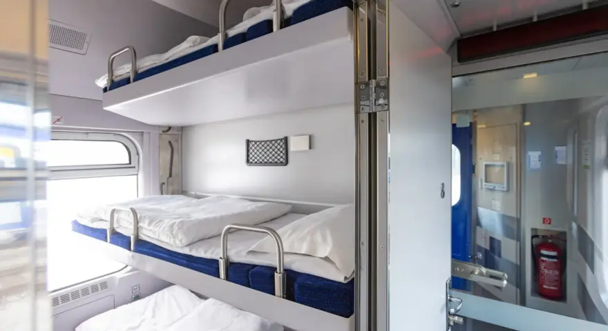 Wygodne łóżka w regiojet wagon sypialny. Trzy piętrowe prycze z pościelą czekają na podróżnych.