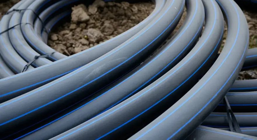 Coiled black hdpe plastic pipes with blue stripes, ready for installation.