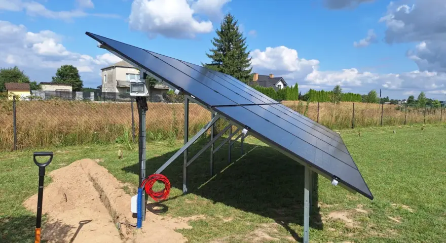 Nowa instalacja fotowoltaiczna w granicy działki, gotowa do podłączenia. Obok koparka i materiały.