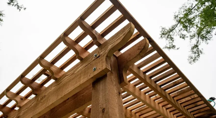 Drewniana pergola z ozdobnymi wspornikami. Dowiedz się, jak wysuszyć mokre drewno konstrukcyjne, aby służyło latami.