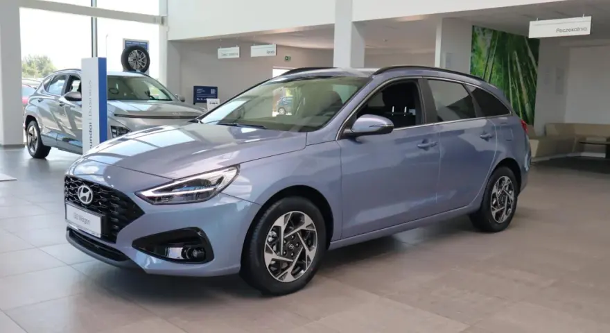 Niebieski Hyundai i30 Wagon z 2015 roku stoi w salonie samochodowym.