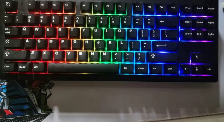 Eine schwarze Tastatur mit bunter RGB-Beleuchtung, die wie ein Regenbogen verstellt ist. Die Tasten leuchten in Rot, Orange, Gelb, Grün, Blau und Violett.