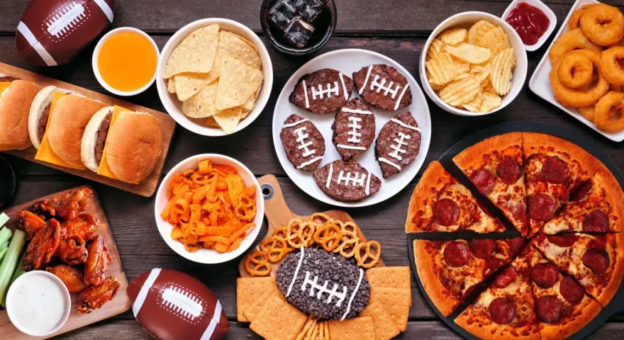 Perfekte Super Bowl Snacks: Pizza, Chicken Wings, Burger, Chips, Brownies in Football-Form und mehr.
