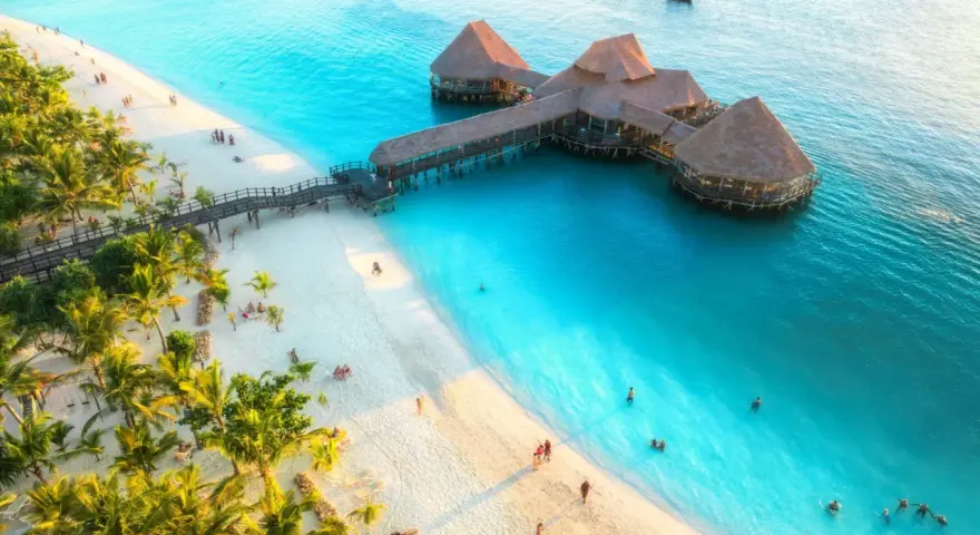 Rajska plaża na Zanzibarze z palmami i restauracją na wodzie. Sprawdź aktualne zanzibar ceny, by zaplanować wymarzone wakacje.