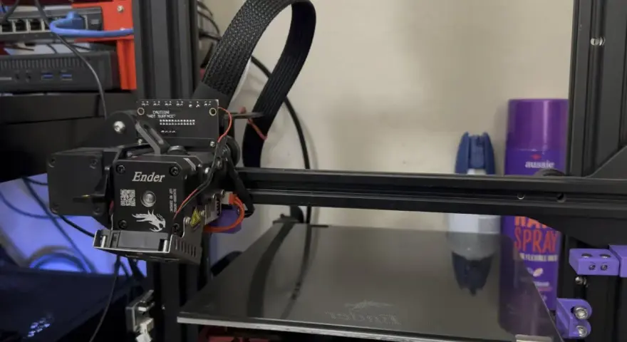 Głowica drukująca klipper ender 3 z kablem w oplocie. Na półce w tle fioletowa puszka z napisem "aussie".