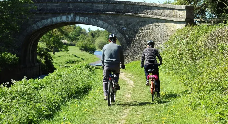 Dwie osoby na rowerach pod kamiennym mostem, cieszą się pięknymi ścieżkami rowerowymi lubuskimi.