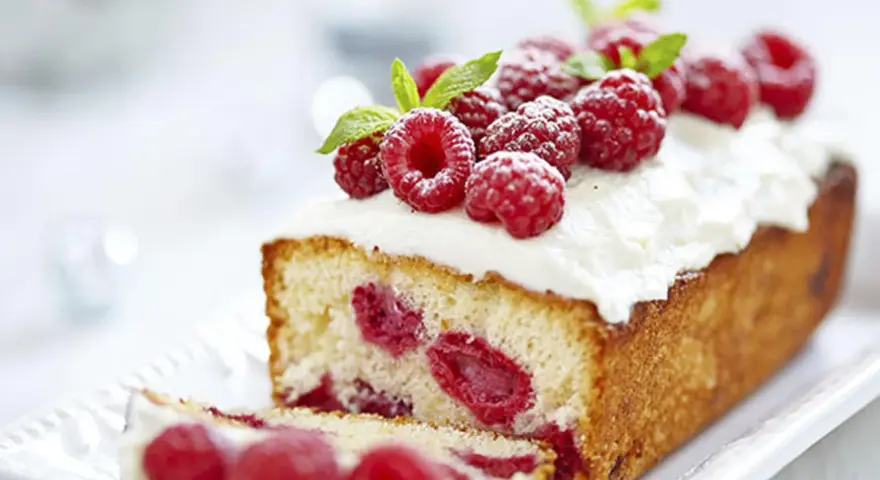Un délicieux framboisier gateau, garni de framboises fraîches et de crème fouettée, prêt à être dégusté.