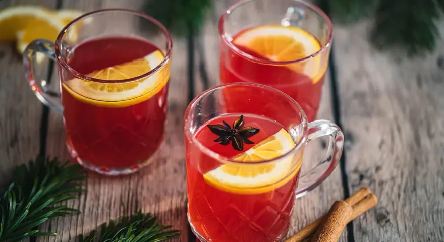 Drei Tassen Kinderpunsch mit Orangenscheiben und Sternanis. Die ideale Temperatur für den Punsch ist warm und einladend.